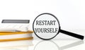 Magnifier with text RESTART YOURSELF with notebook, calculator on the white background