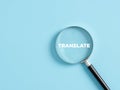 Magnifier with the text translate on blue background. Language translation Royalty Free Stock Photo