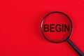 Magnifier with the word - BEGIN, on a red background