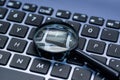 Magnifyer glass on laptop computer keyboard in blue tone, Royalty Free Stock Photo