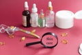 magnifying glass against the background of blurred face serums and dermoroller