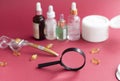 magnifying glass against the background of blurred face serums and dermoroller