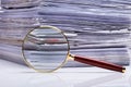 Magnifying Glass On The Background Of The Stacked Paper Files