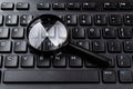 Magnifying glass on the black computer keyboard closeup. Find keywords and online resources, network search, Internet security Royalty Free Stock Photo