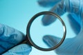 magnifying glass in blue medical scientific gloves