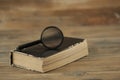 Magnifying glass with close old book on wood table