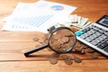 Magnifying glass, coins, calculator and statistics on the table