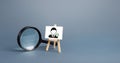 Magnifying glass and an easel with a new hired employee. Recruiting and HR management. Hiring new workers, staffing. Headhunters