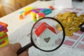 Magnifying glass focus on house model on golden coins money, rea