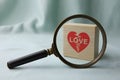 A magnifying glass focuses on a block with a broken heart, symbolizing relationship issues. Royalty Free Stock Photo