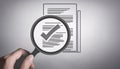 A magnifying glass focuses on documents with checkmarks, symbolizing scrutiny and verification in a detailed illustration