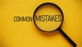 Magnifying glass focusing on \'MISTAKES\' with yellow background and common errors text Royalty Free Stock Photo