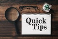 Magnifying glass, glasses, cactus and notebook with QUICK TIPS word on wooden table