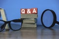A magnifying glass, glasses ,a stack of book and red wooden cube written with Q and A or questions and answers Royalty Free Stock Photo