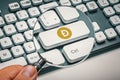 magnifying glass in hand focused on computer key dogecoin logo