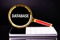 Magnifying glass revealing the word database above a modern keyboard in a dark environment