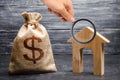 Magnifying glass is looking at a bag with money and a house with a large doorway. Concept of real estate acquisition Royalty Free Stock Photo