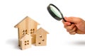 Magnifying glass is looking at the City of wooden houses on a white background. The concept of urban planning, infrastructure proj Royalty Free Stock Photo