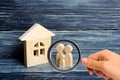 Magnifying glass is looking at the Family is standing near the house. Wooden figures of persons stand near a wooden house. Royalty Free Stock Photo