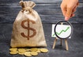 Magnifying glass is looking at the green arrow up on the chart and a Bag with money. concept of increasing profits and revenues Royalty Free Stock Photo