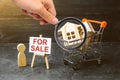 Magnifying glass is looking at the supermarket cart with houses and man with a poster for sale. concept of selling a home Royalty Free Stock Photo