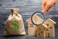 Magnifying glass is looking at the three houses near a bag with money. real estate acquisition and investment. Royalty Free Stock Photo