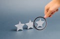 Magnifying glass is looking at three stars on a gray background. The concept of rating and evaluation. The rating of the hotel Royalty Free Stock Photo