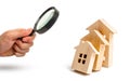 Magnifying glass is looking at the Wooden houses fall on each other like dominoes. concept of falling prices for house purchase