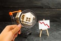 Magnifying glass is looking at the wooden houses in a supermarket cart and up down. Reduction of demand for housing and real Royalty Free Stock Photo