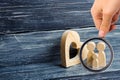 Magnifying glass is looking at the young family with a child is standing near a wooden heart. Love and loyalty Royalty Free Stock Photo