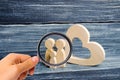 Magnifying glass is looking at the young family with a child is standing near a wooden heart. Love and loyalty, Royalty Free Stock Photo