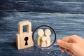 Magnifying glass is looking at the young family with children is standing near a wooden padlock. concept of a strong family Royalty Free Stock Photo