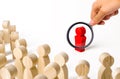 A magnifying glass looks at a red figurine of a man near a crowd. Leader, leadership and initiator of action. work or business