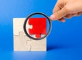 A magnifying glass looks at a red wooden puzzles on a blue background. Individual opinion. Stand out from the crowd. Uniqueness Royalty Free Stock Photo