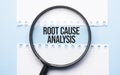 Magnifying glass loupe with sign Root Cause Analysis between two paper sheets on the blue table Royalty Free Stock Photo