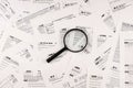 Magnifying glass lying over heap of paper documents. Investigation and financial audit