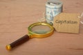 Magnifying glass and money banknotes with text CAPITALISM