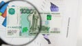 Magnifying glass and money - business background. Thousand ruble bill under a magnifying glass is being inspected