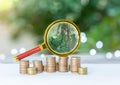 Magnifying glass on money stacks that gradually increase Royalty Free Stock Photo