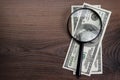 Magnifying glass and money on wooden background Royalty Free Stock Photo