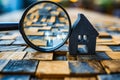 Magnifying glass next to tiny house made of wooden blocks. Generative AI Royalty Free Stock Photo