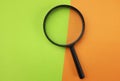 Magnifying glass on the on a orange and green paper background