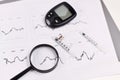 Magnifying glass over blood glucose sugar level diagrams of person with diabetes with syringe, vial and glucose meter