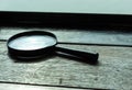 Magnifying glass is placed on a wooden table. Royalty Free Stock Photo