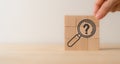 Magnifying glass and question mark icon on wooden cube blocks. Question mark, problems and root cause analysis. Royalty Free Stock Photo