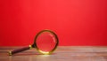 Magnifying glass on a red background. Search and analysis, analytics and study. Pay attention to details and problems. Find