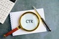 Magnifying Glass Reveals the Abbreviation CTR on a Notepad With a Calculator and Pen on a Textured Table Surface Royalty Free Stock Photo