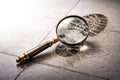 A magnifying glass and a shoe footprint on a wet tile. Royalty Free Stock Photo