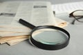 Magnifying glass and stack of newspapers on table, closeup. Job search concept Royalty Free Stock Photo