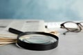 Magnifying glass and stack of newspapers on table. Job search concept Royalty Free Stock Photo